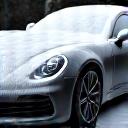 A black car covered in thick white snow foam during a pre-wash.